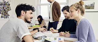 A group of students engaged in discussion during a study session, exchanging ideas with textbooks and notes, creating a collaborative and dynamic learning environment. © © Goethe-Institut Ausbildung Support Sessions