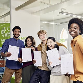 A group of young people proudly displaying their certificates, smiling and celebrating their achievements together.