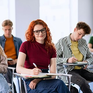 A diverse group of students engaged in learning while sitting at their desks in a bright classroom.