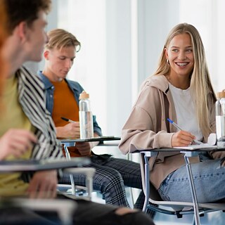 A classroom scene featuring students sitting together, collaborating and studying at their desks.