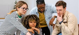 Four people are concentrating on a document