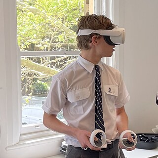 Boy in a classroom wearing virtual reality glasses, fully immersed in his digital experience.