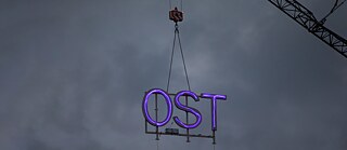 The ”OST“ (east) inscription on the roof of the Volksbühne in Berlin is removed with a crane