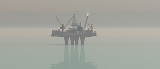 An oil platform at sea. It is reflected in the water.