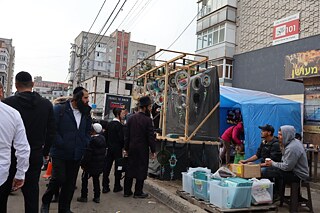 Lokale Verkäufer und Chassidim auf den Straßen von Uman während der Rosch ha-Schana-Feierlichkeiten. Einige der Stände sind durch Netze geschützt, um Diebstähle zu verhindern.