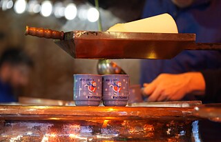 Ein Mitarbeiter auf dem Weihnachtsmarkt in Hamburg-Wandsbek füllt Feuerzangenbowle in einen Becher. 