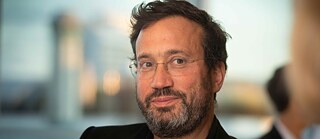 A headshot of Eyal, a man with a beard and glasses