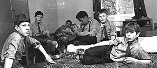 A group of British boarders sit on the beds in their dormitory