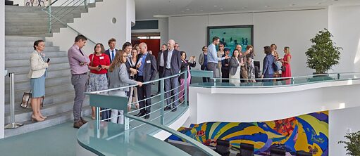 Participants of the network meeting stand in a group on one floor in the Federal Chancellery in Berlin.