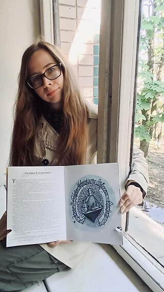 Kateryna Yehorushkina mit einem „verwundeten“ Buch, zu dem sie als Autorin ein Kapitel beigesteuert hatte. Obuchowytschi, Oblast Kyjiw