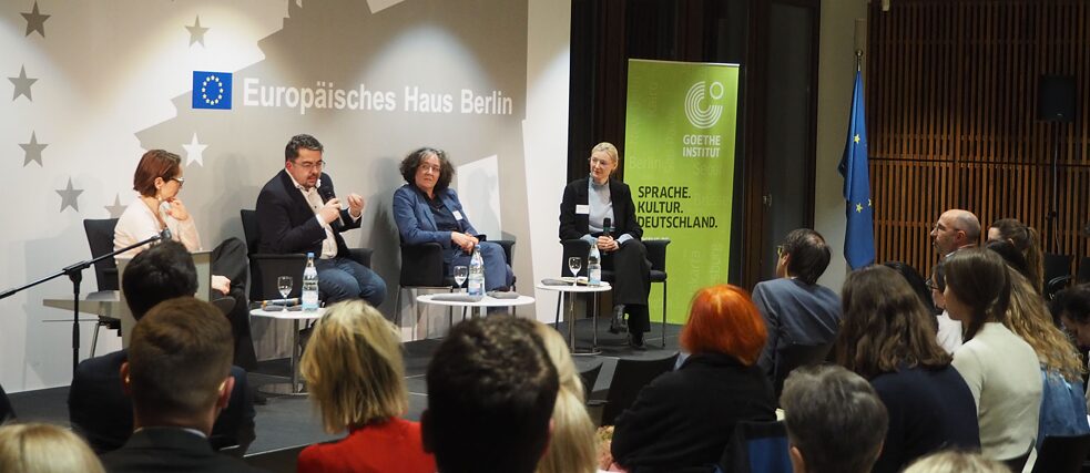 Discussion on the podium in the European House in Berlin with four people and an audience.