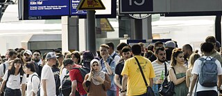 Passagiere warten auf einem Bahnsteig auf einen Zug