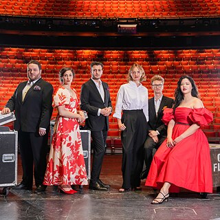 Singers in Opera Australia's Young Artist Programme. 5 people, all in concert attire. The auditorium can be seen in the background. 