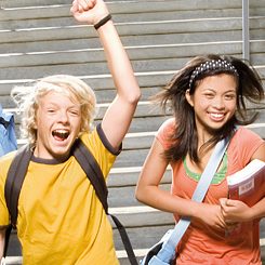 Kilku nastolatków (11–15) skaczących ze schodów na zewnątrz budynku i śmiejących się, portret