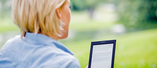 Junge Frau mit E-Book-Reeder im Park