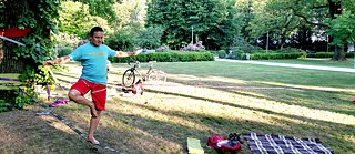 一位男士在公園裡走繩上鍛鍊平衡感。