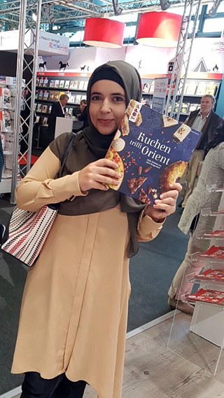 Huda al-Jundi au salon du livre de Francfort tenant son livre «Le gâteau rencontre l'Orient»