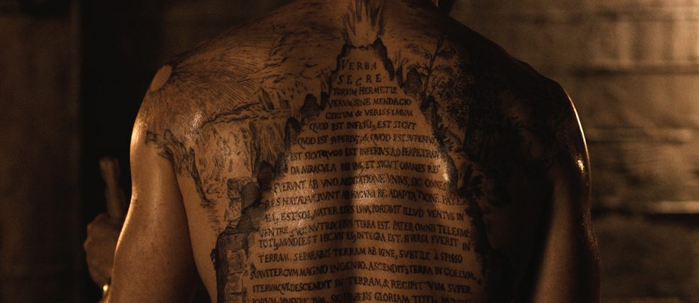Un tatuaje con una inscripción en latín en la espalda de un hombre 