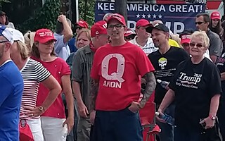 Stúpenec teórie QAnon na demonštrácii podporovateľov Donalda Trumpa v Manchestri (štát New Hampshire) v auguste 2019. V teórii QAnon sa Trumpova administratíva považuje za záchrancu detí v tzv. „detských továrňach“.