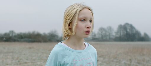 A girl stands on a meadow and seems lost