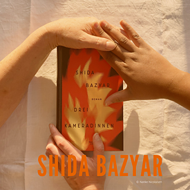 Das Buchcover von Shida Bazyars "Drei Kameradinnen" wir in Abensonne von Händen gehalten