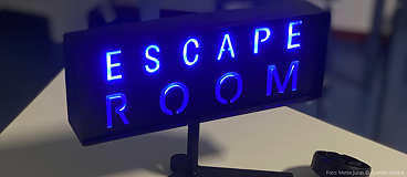 Leuchtschild mit Aufschrift in neon-blau "Escape-Room" 