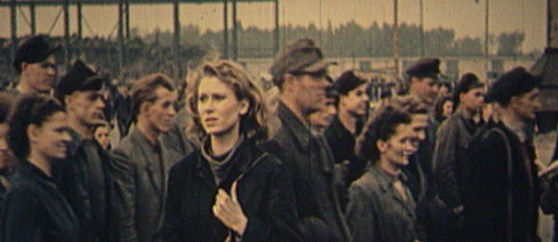erinnert an ein Archivfoto mit einem körnigen Bild einer Menge von Arbeitern und einer Frau im Vordergrund, die aus einem anderen Film zu stammen scheint