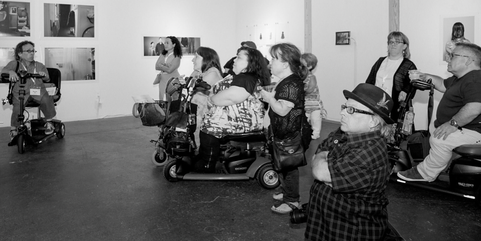 In der Ausstellung „Composing Dwarfism: Reframing Short Stature in Contemporary Photography", die von Dr. Amanda Cachia 2014 im Space4Art in San Diego, USA, kuratiert wurde, wurden die Werke in Rücksichtnahme auf Besucher*innen mit Zwergenwuchs niedriger gehängt, wodurch sich eine geschickte Kombination von inklusiver Gestaltung und Ausstellungsthema ergab. 