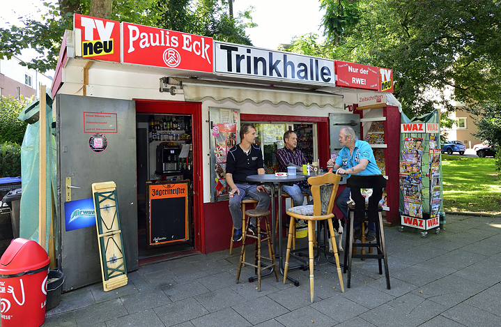 Three men sitting in front of the Pauli's Eck kiosk in Essen