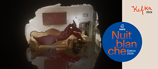 Sur l’image extraite de la vidéo, un bernard-l’hermite rouge à taille humaine est allongé sur un canapé au milieu d’un salon aux contours flous