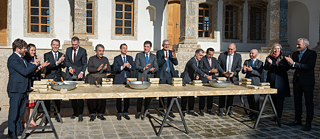 Eine Personengruppe in formeller Kleidung vor einem historischen Gebäude 