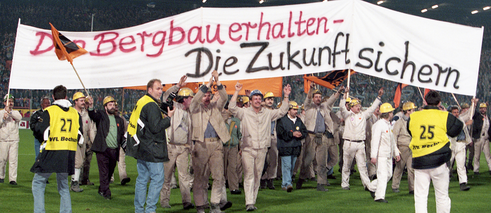 Miners demonstrate with a poster against the closure of mines at the Ruhrstadion in Bochum