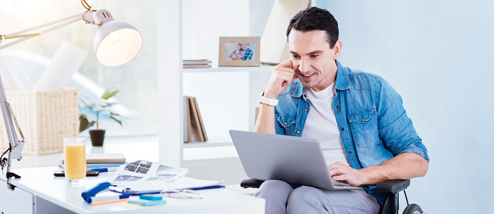 Man in wheelchair sitting at desk with laptop