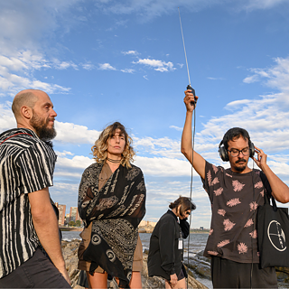 Workshop in Montevideo anlässlich 100 Jahre Radio, vier Personen stehen mit Radioausstattung am Meer
