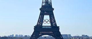 Der Eiffelturm vor dem Stadtpanorama von Paris. Am Eiffelturm sind die olympischen Ringe angebracht.