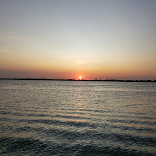 Das Foto zeigt den Sonnenuntergang in Porto Alegre über dem Wasser des Guaiba.