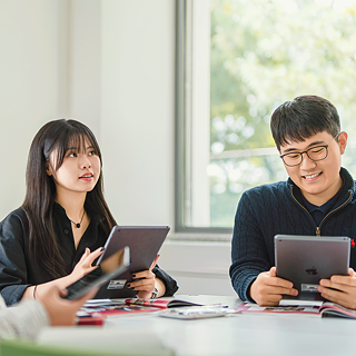 두 사람이 한 방에 앉아 iPad에 집중하며 독일어 수업에서 협업 또는 독립 과제를 수행합니다.