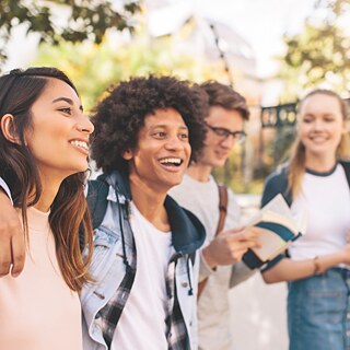 A group of young individuals smiling and engaging with one another in a joyful atmosphere.