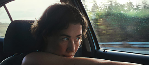 A woman with short hair sits in a car. 