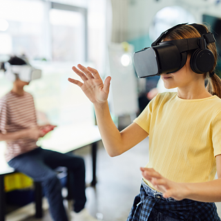 A girl in a classroom wearing virtual reality glasses, immersed in an interactive learning experience