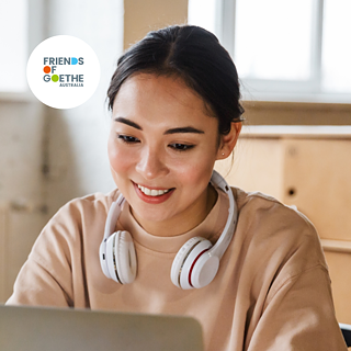  A woman wearing headphones smiles while working on her laptop, enjoying her time and focused on her task