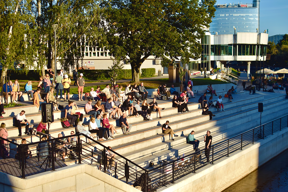 People sitting on stairs close to the riverbank in the sun