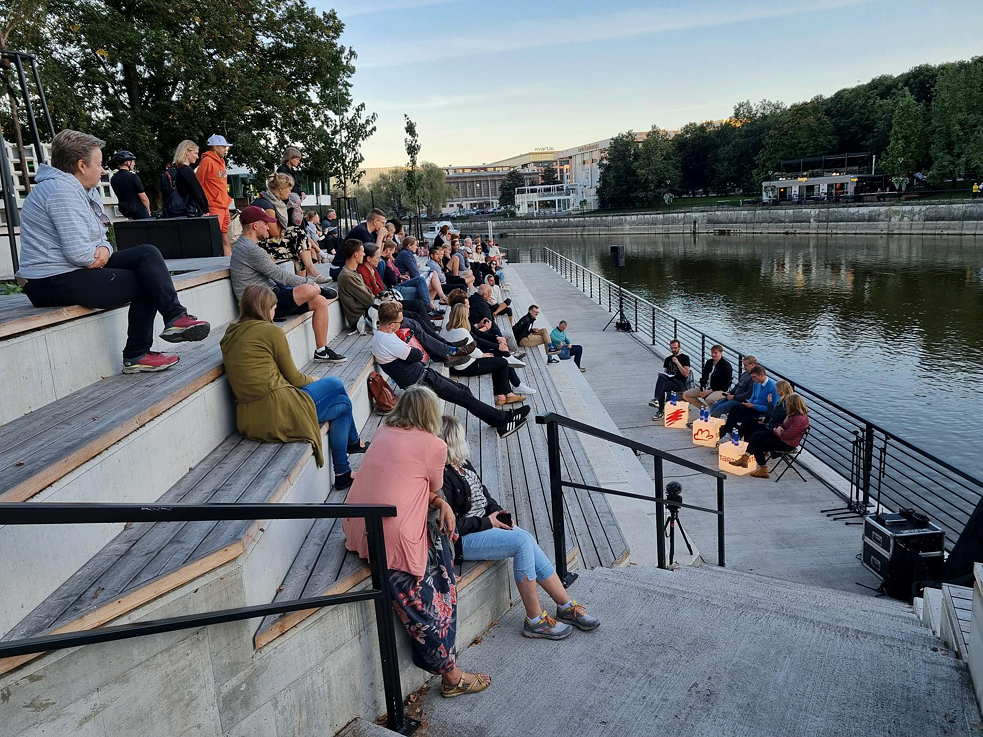 People sitting on stairs close to the riverbank in the sun