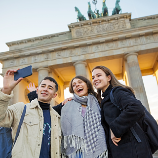 Three friends taking a selfie at the Brandenburger Gate in Berlin.