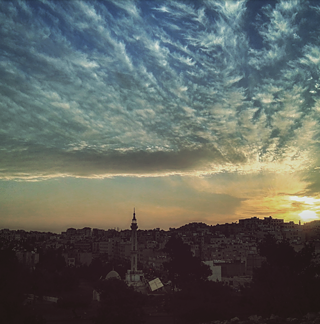 Sonnenuntergang in Amman, aus dessen Mitte sich ein Turm erhebt