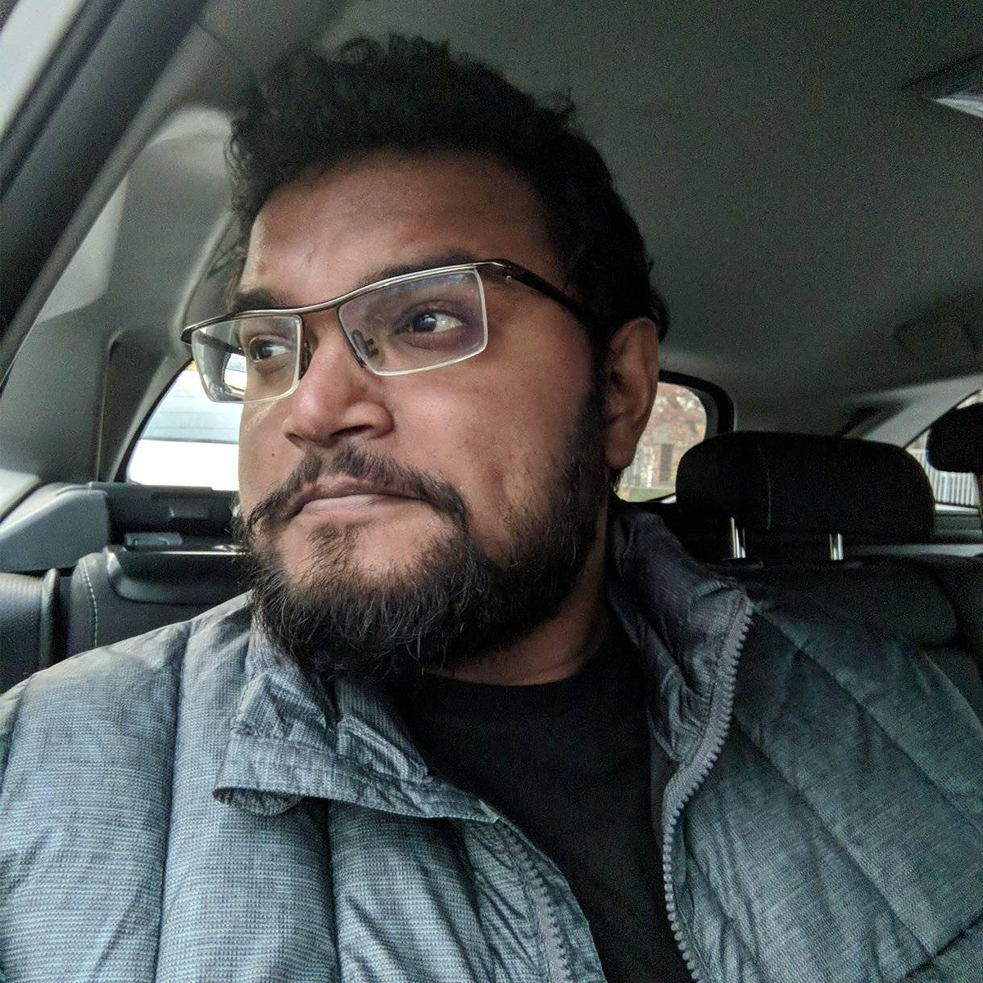 Ảnh chân dung của Yudhanjaya Wijeratne; anh ngồi trong xe ô tô và tóc cắt ngắn và đeo kính